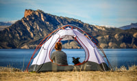 lady camping in a tent with her dog by they lake
